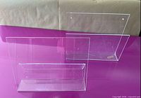 Two clear acrylic holders standing on surface, both fully visible