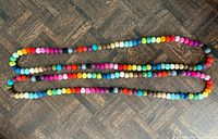 Both colourful wool bead necklaces laid out flat to show full length and colour variety