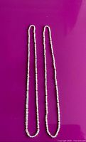 Two identical seed pearl necklaces with interspersed gold beads laid flat to show full length and design