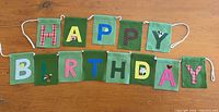 Full view of felt “Happy Birthday” banner with 15 green squares on rope