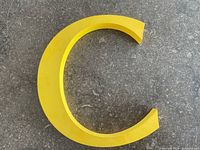 Front view of yellow plastic letter C on stone background