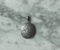 Front view of engraved silver oval locket pendant