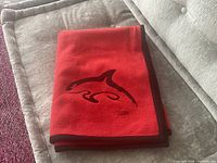 folded blanket showing orca embroidery and black trim