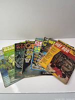 Seven assorted magazines fanned out on white surface