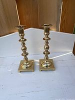 Front view of both brass candlestick holders on white surface