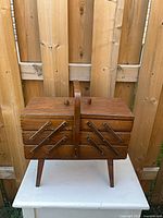 Closed wooden accordion sewing box on legs