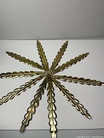 Eight brass tone metal leaves arranged radially showing overall style and quantity