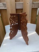 Full view of carved hardwood folding base standing on tabletop