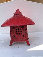 Front view of red cast iron pagoda lantern showing lattice window, door and feet