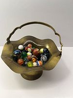 Brass basket holding assorted marbles, full view