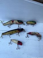 Overview of five vintage wooden lures on white surface