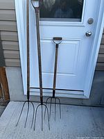 Two pitch forks leaning against door showing full length