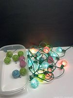 String of lights coiled beside spare globes in plastic container