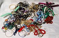 Overview of tangled jewelry pile on white surface