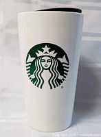 Front view of white Starbucks travel mug showing green siren logo and black lid