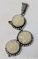 Full view of sterling silver pendant showing three carved discs and bail