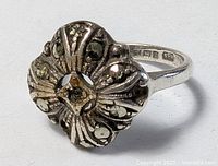 Three-quarter view of ring showing floral face and stones