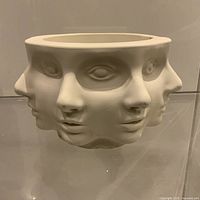 Front view showing multiple abstract faces around bowl