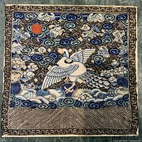 Full view of embroidered rank badge showing bird, sun, clouds, border