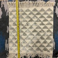 Front view of square wool mat with vertical tape measure showing height around 16 inches