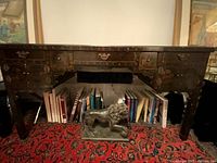 Full view of desk front showing drawers, doors, brass pulls, painted decoration, and scale with books beneath