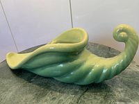 Side view of green ceramic cornucopia planter