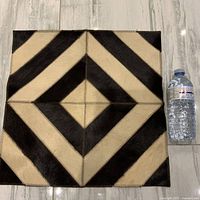 Front of square cowhide mat next to water bottle for scale