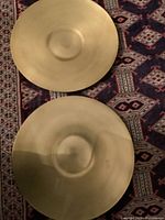 Both brass plates displayed side-by-side on patterned textile