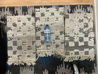 Three hand-woven Moroccan wool/silk table mats with cream fringe and a water bottle for scale