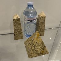 Two obelisks and pyramid beside water bottle for scale