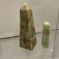 Large and small green marble obelisks standing upright