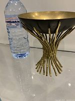 Full view of brass and enamel bowl beside water bottle for scale