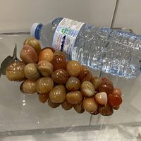 Full view of agate grape cluster beside water bottle for scale
