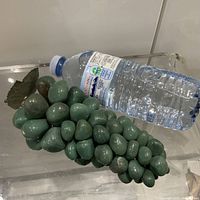 Full view of green hardstone grape cluster beside water bottle for scale