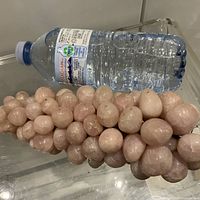 Full view of rose quartz grape cluster beside water bottle for scale