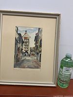 Full view of framed painting beside water bottle for scale