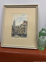 Framed watercolour next to bottle for scale