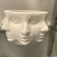 Front view of white ceramic bowl showing three abstract faces