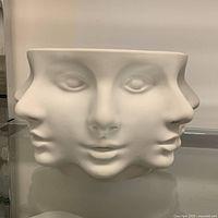 Front view of white ceramic bowl with multiple abstract faces