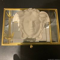 Top view of glass box showing sculpted mythological face and butterfly accent