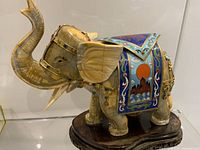 Left front view showing carved elephant, brass and cloisonné details, wood base