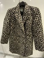 Front view of leopard print coat hanging, shows full length and pattern
