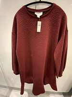 Front view of maroon textured dress on hanger showing overall design