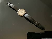 Full view of watch with leather strap laid flat