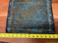 Underside of woven mat with measuring tape indicating width