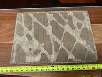 Front view of woven wool mat showing tan and white pattern with measuring tape for scale