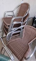 Stacked taupe rattan-style chairs showing aluminum frames and woven seats