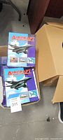 Stack of Aircraft World hardcover books partially in open cardboard box