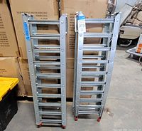 Full view of both folded aluminum ramps standing upright showing overall design