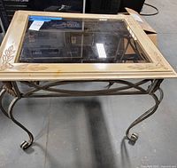 Oblique view of entire table showing glass top, wood frame, metal legs